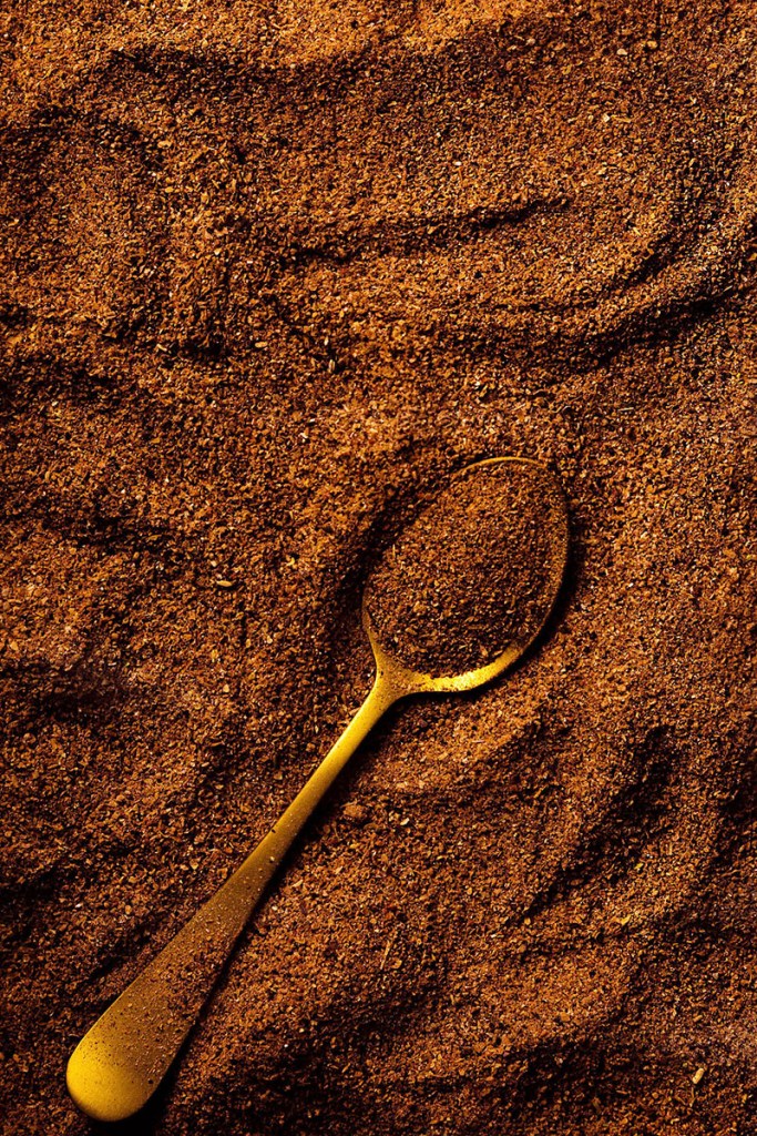 Ground carob close up with gold teaspoon. 