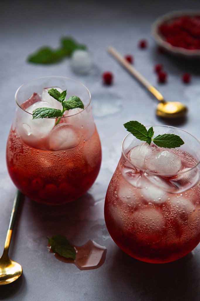 Two glasses with red drink and ice with mint leaves.
