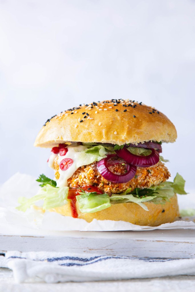 Veggie burger in the bun with the red onion slices and sauce.