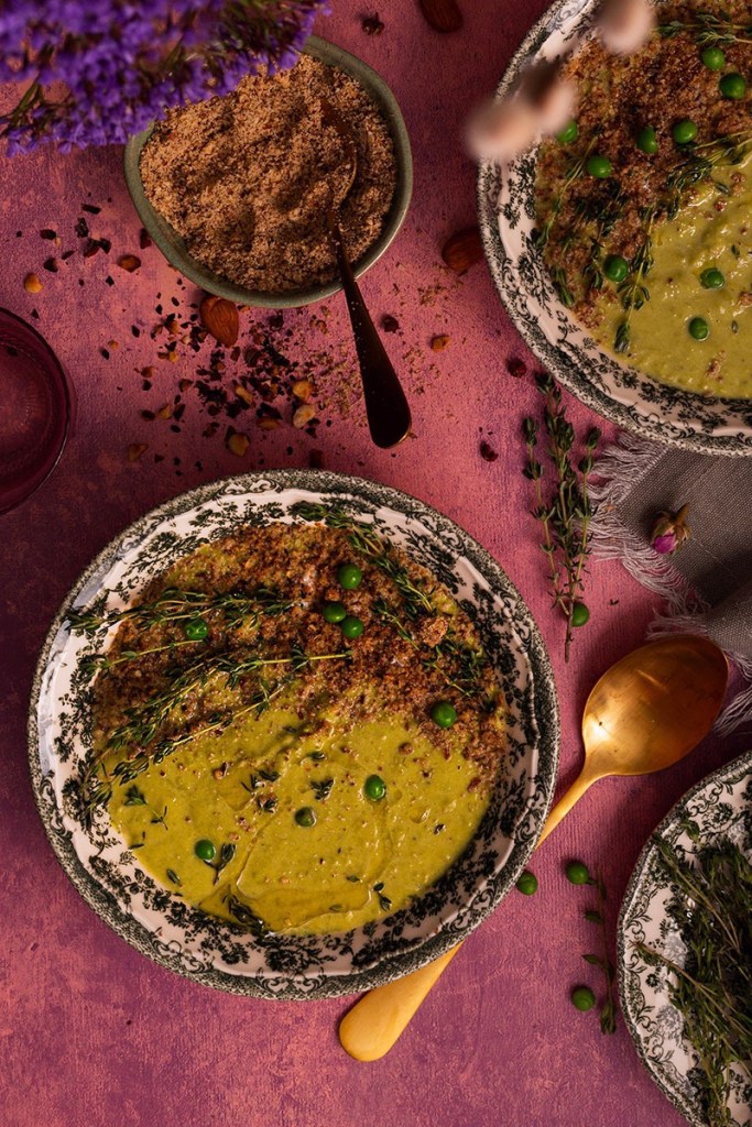 Creamy vegan Pea and Leek Soup with coconut milk, fresh thyme, and dukkah sprinkle in the bowls on the table. 
