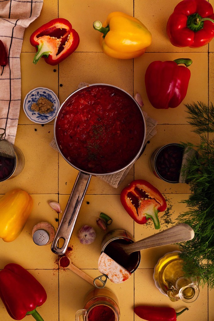 Vegan Stuffed Peppers with Beans and Vegetables with stuffing in the saucepan on the yellow tiles.