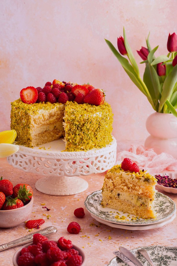 Indulgent Mascarpone and White Chocolate Pistachio Lemon Torte, cake with fresh strawberries and raspberries. 