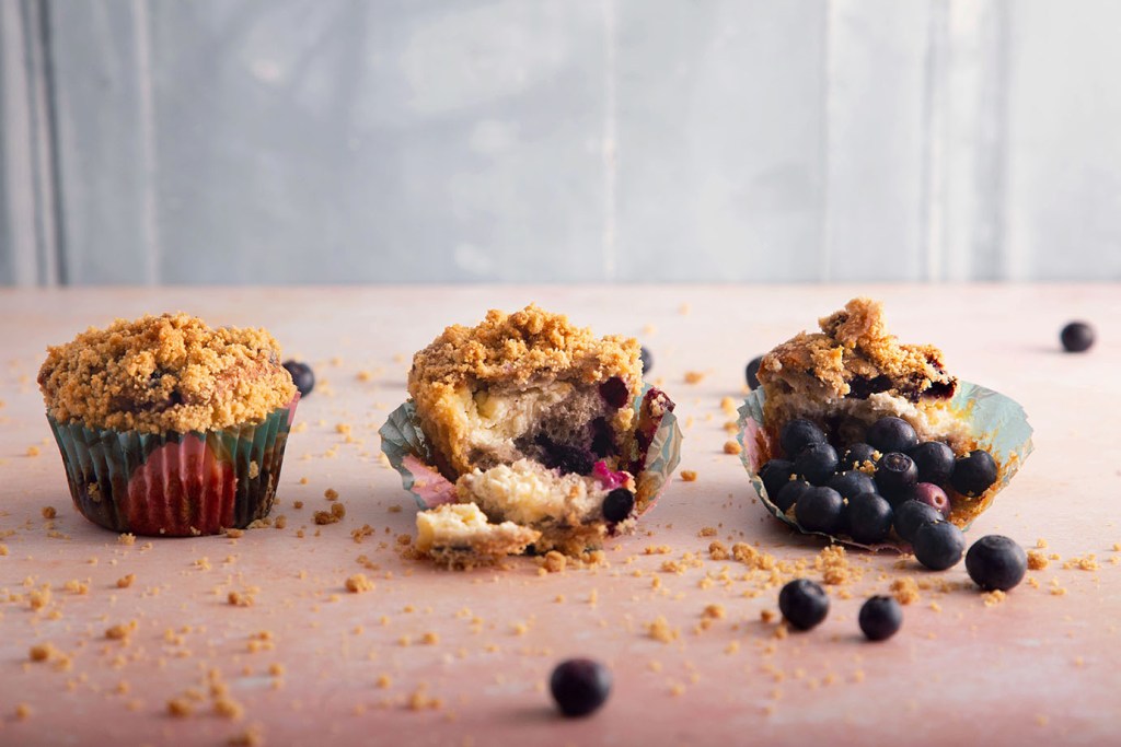 Three blueberry muffins with cheesecake filling and crunchy topping