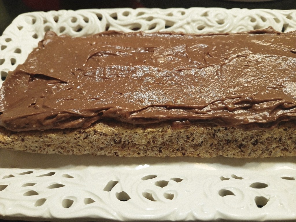 Torte of walnut dacquoise layered with vanilla and chocolate crème mousseline, assembling the torte.