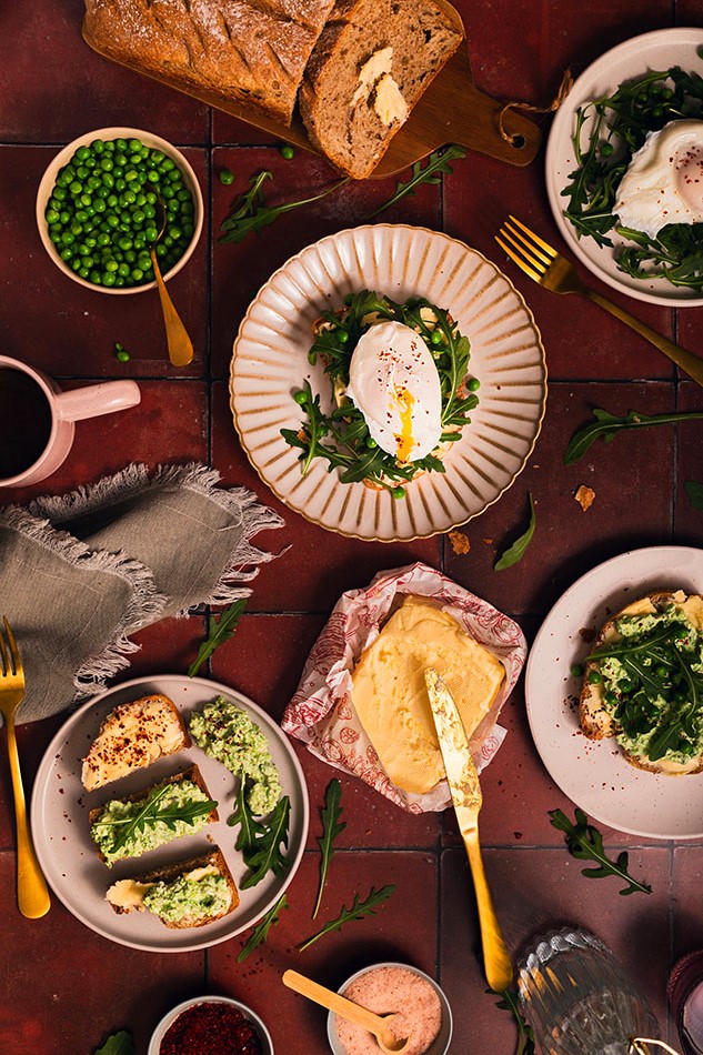 Breakfast table with the freshly baked bread, butter,poached eggs and salad leaves and peas.