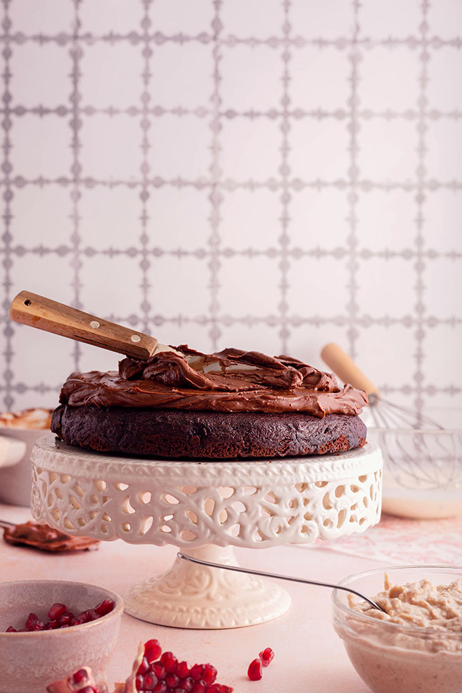 Chocolate cake with chocolate cream on the cake stand, process shot. 