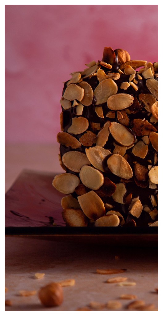 Torte of walnut dacquoise layered with vanilla and chocolate crème mousseline, coated with roasted almond flakes.