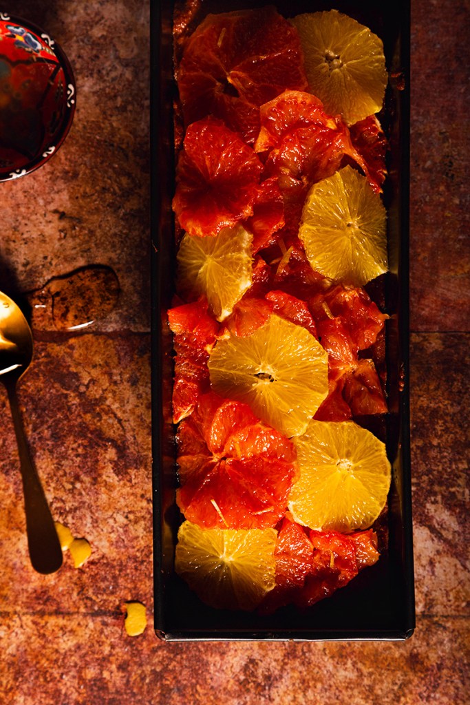 Loaf cake with orange slices in a loaf pan.