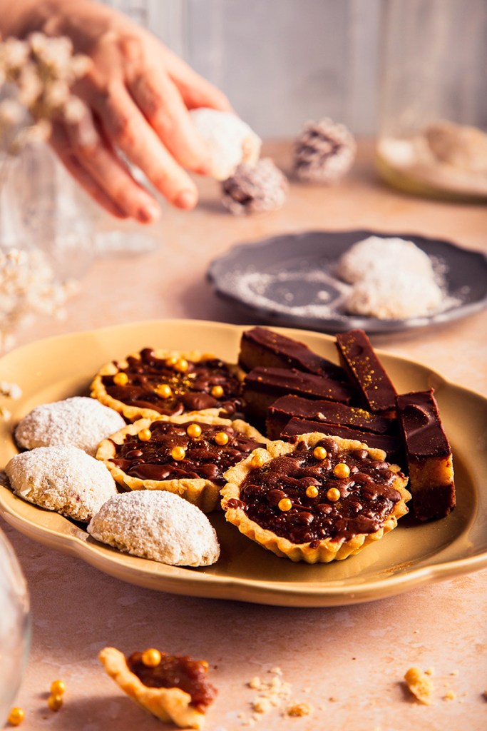 Bajadera-no bake dessert made from ground biscuits, walnuts, and melted butter, tartlets with chocolate filling, and walnut biscuits on the plate.