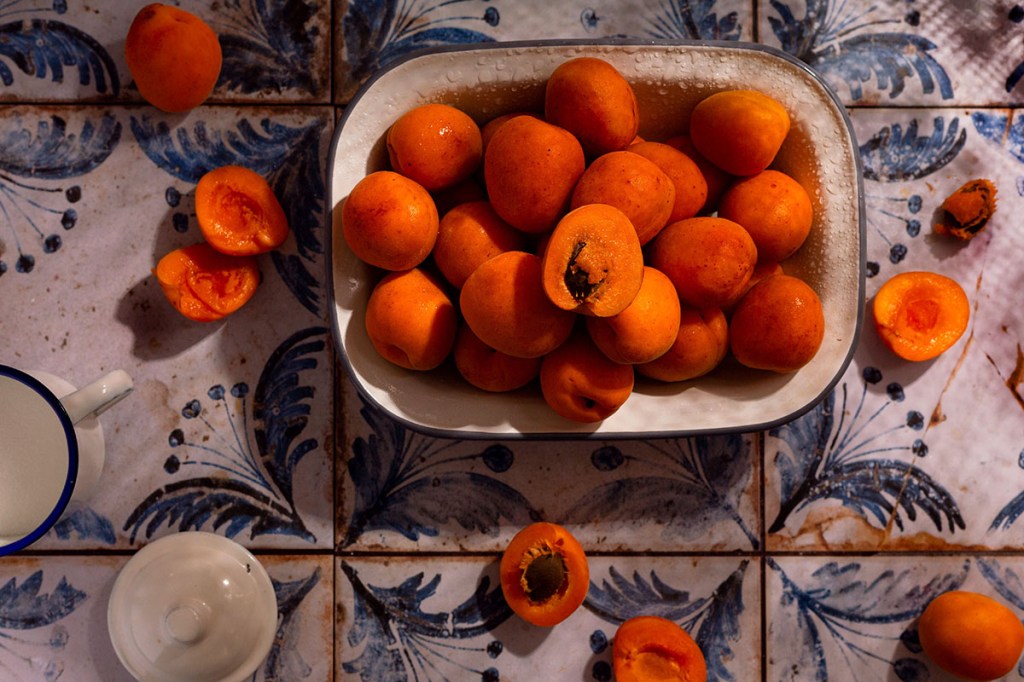 Fresh apricots for homemade apricot jam on blue tiles.